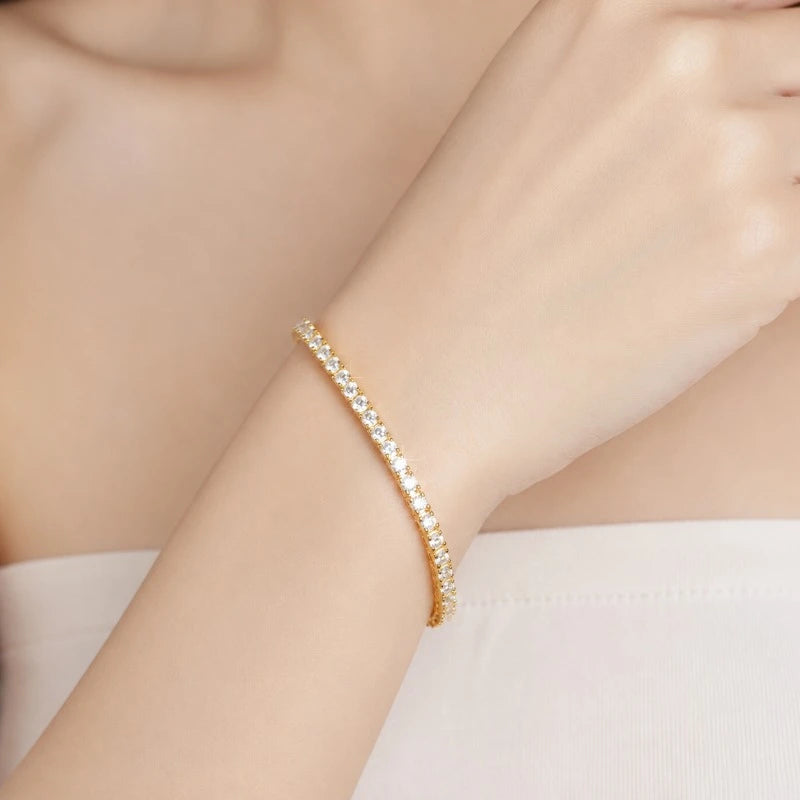 Gold-tone moissanite tennis bracelet worn on a woman's wrist.