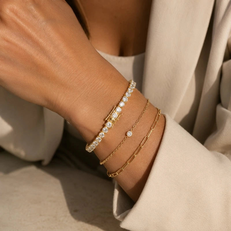 Gold-tone moissanite tennis bracelet styled in a layered bracelet stack.