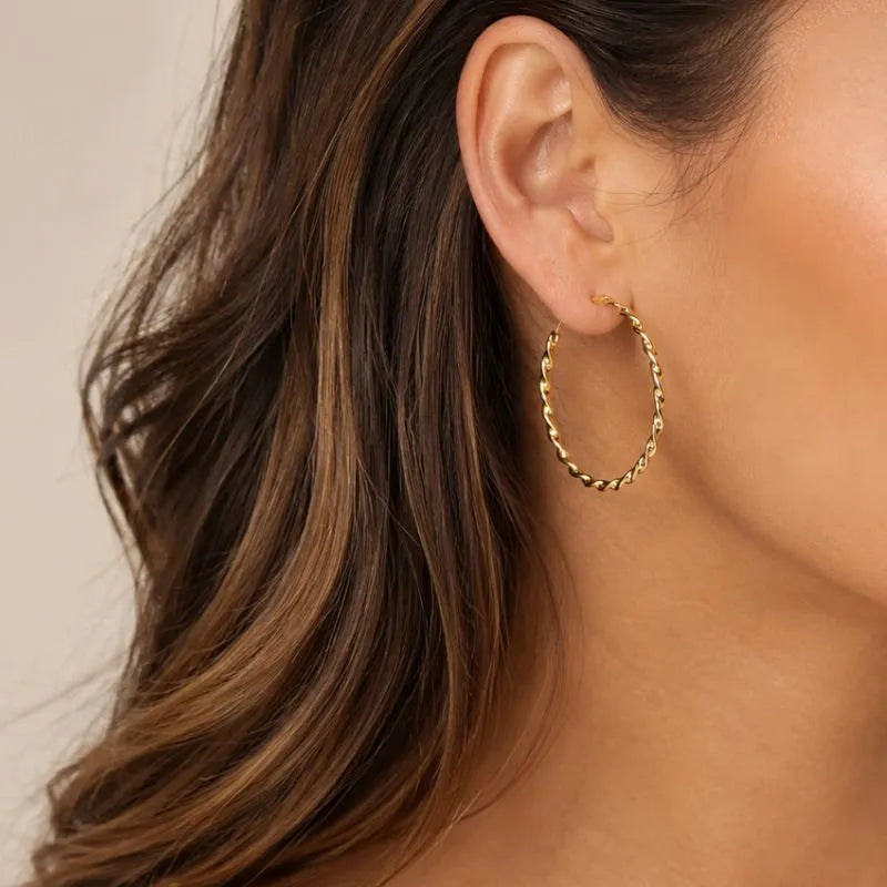 Woman wearing the Aurélie gold-colour twisted hoop earrings