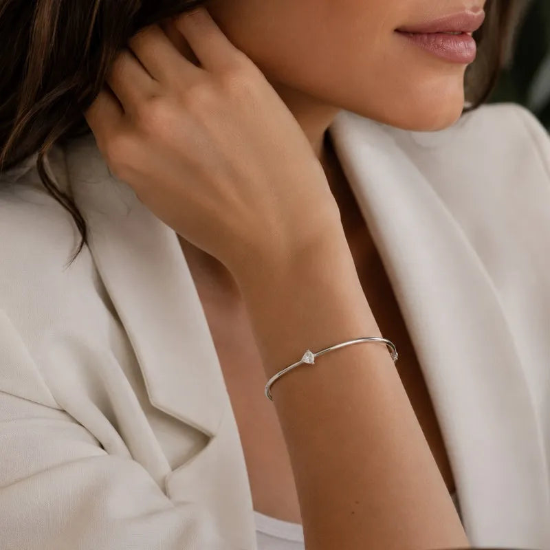 Woman styling the Céleste pear-cut moissanite bangle with an elegant neutral outfit