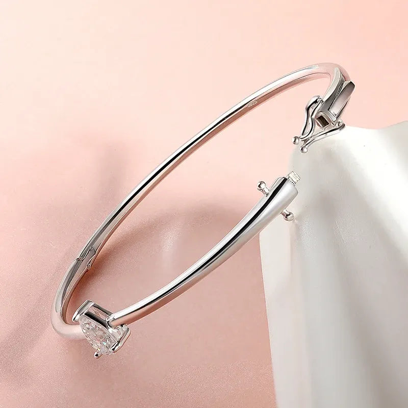 Céleste polished 925 sterling silver bangle with a pear-shaped moissanite centre stone