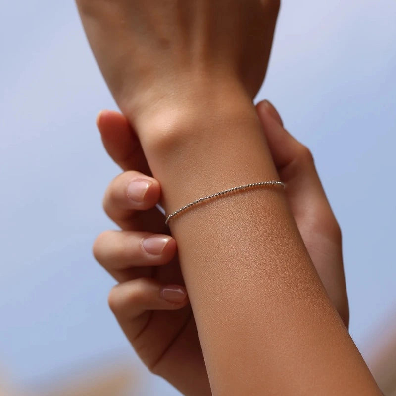 Woman wearing an elegant Silver Satellite Bead Bracelet crafted in genuine 925 sterling silver with a delicate minimalist chain.