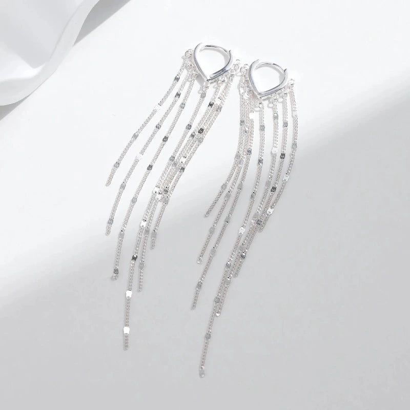 Close-up of long tassel hoop earrings showing the polished geometric hoop and delicate silver chain strands