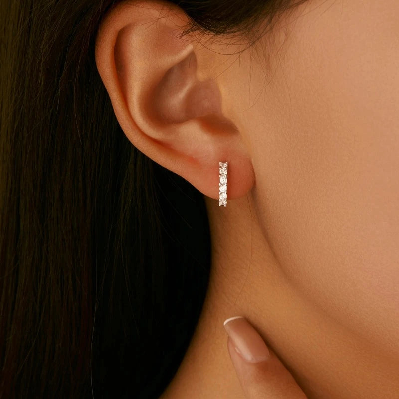 Woman wearing elegant Small Moissanite Hoop Earrings in genuine 925 sterling silver with brilliant sparkling moissanite stones.