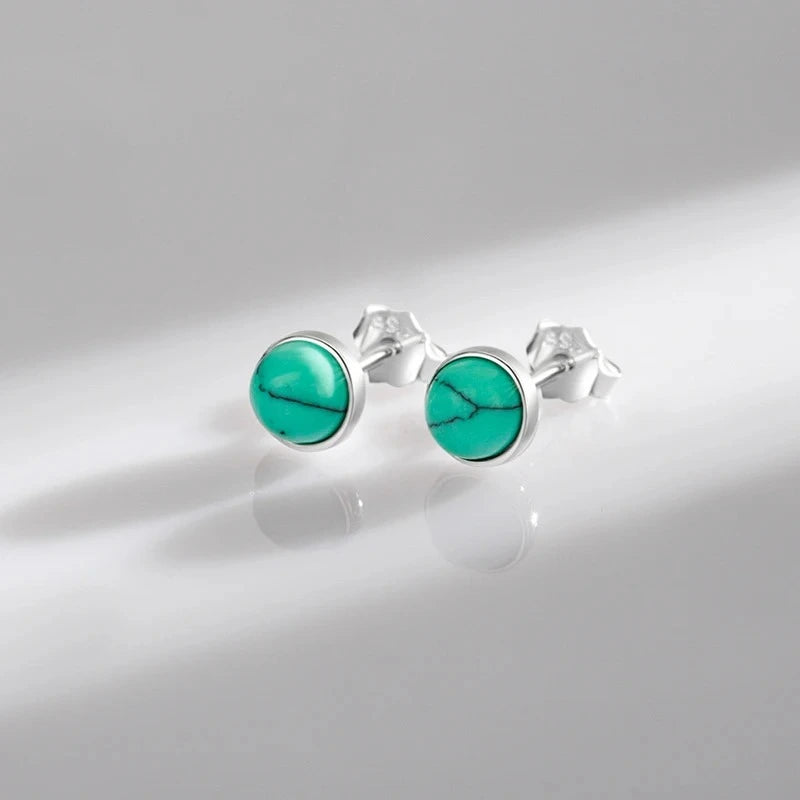 Close-up of round turquoise stud earrings showing the polished bezel setting and 925 sterling silver finish